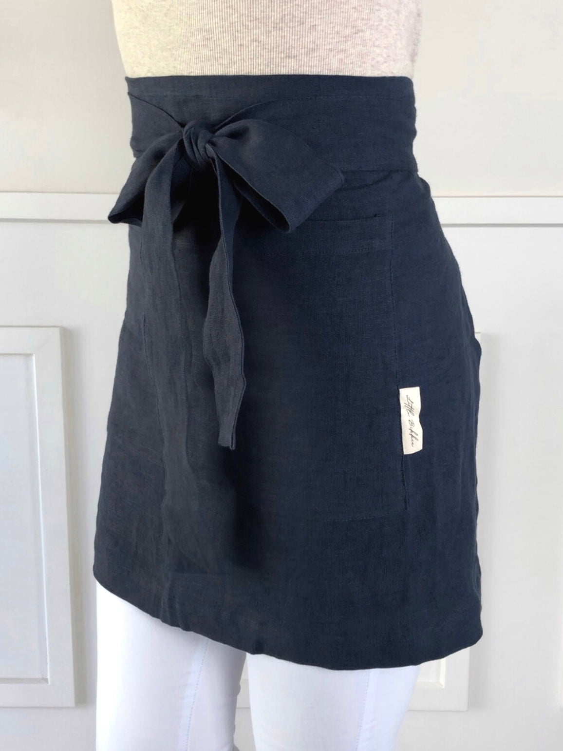 100% linen half waist apron. Large front pocket. Long ties can be fastened at the back or at the front, creating a large bow. Navy blue colour way.