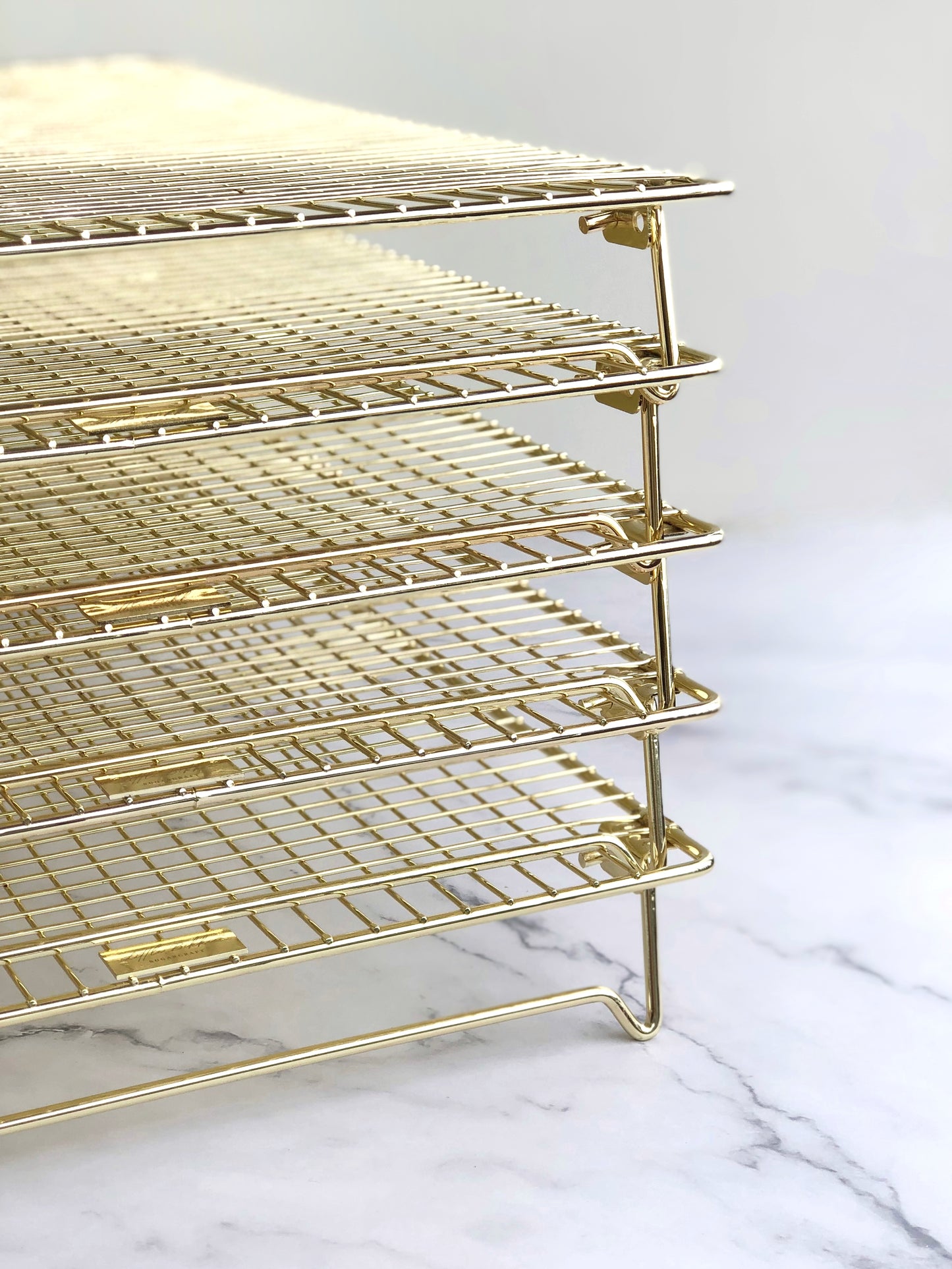five gold cooling racks stacked on top of each other