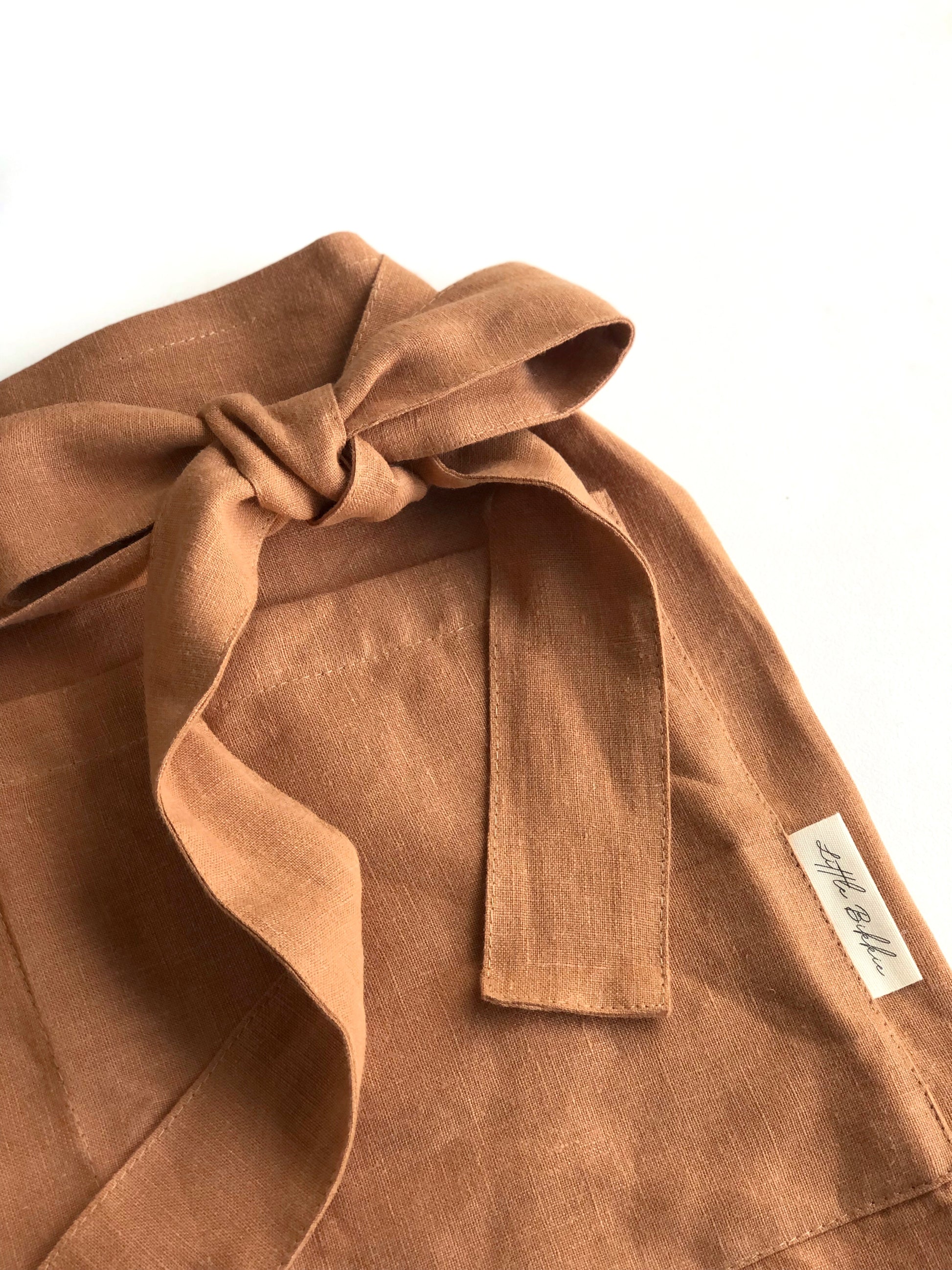 100% linen half waist apron. Large front pocket. Long ties can be fastened at the back or at the front, creating a large bow.Both protective and stylish. Terracotta colour way.