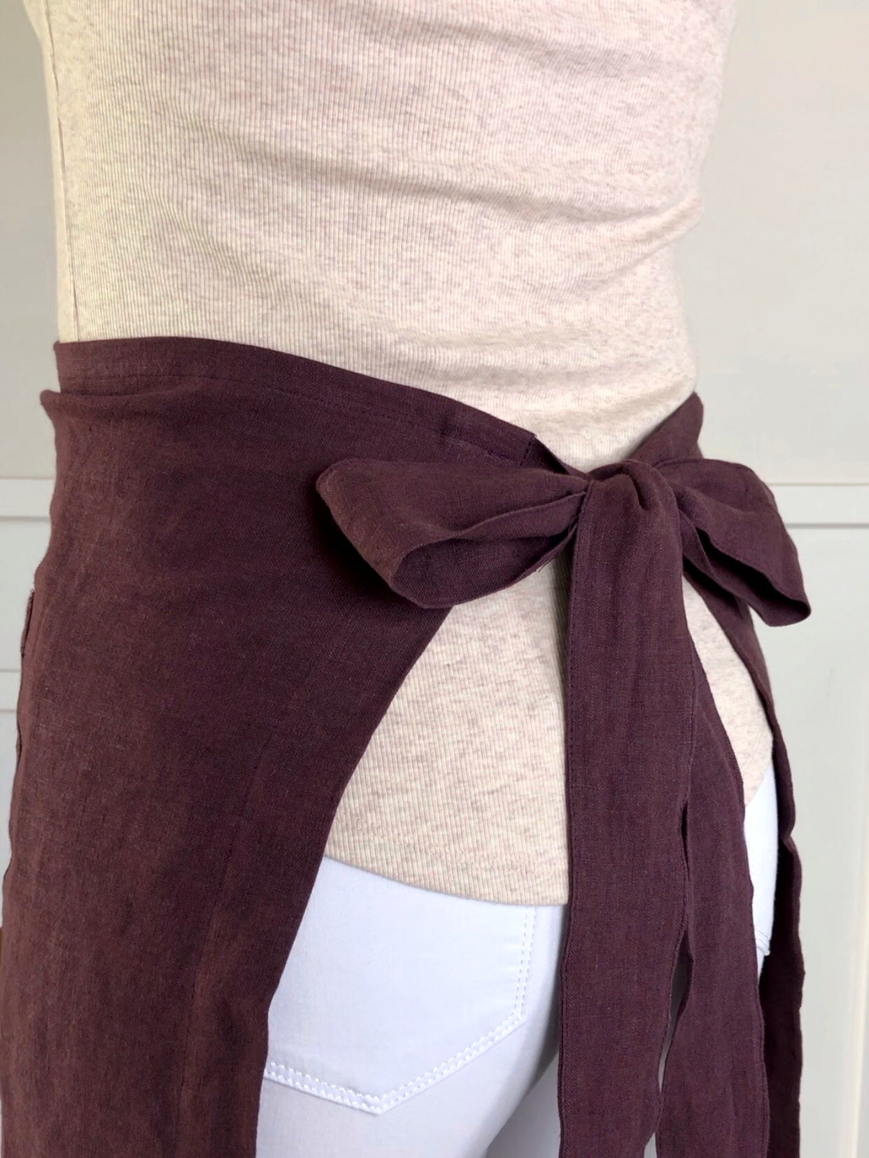 100% linen half waist apron. Large front pocket. Long ties can be fastened at the back or at the front, creating a large bow. Plum colour way.